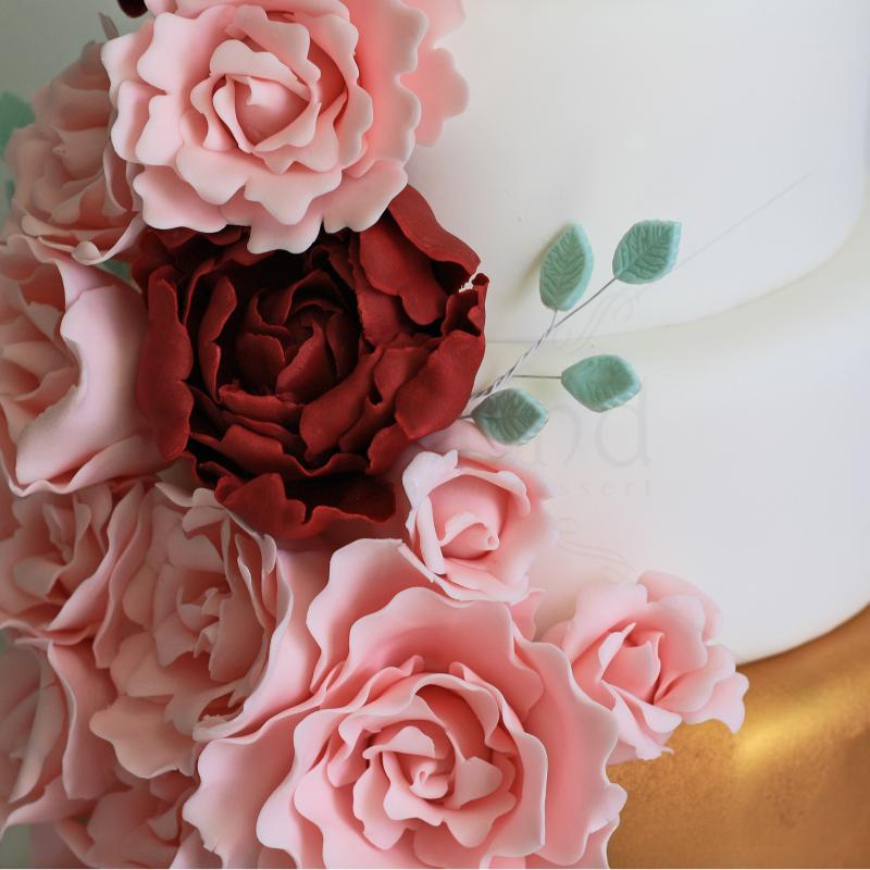 Tort de nunta modern alb cu auriu si flori roz si grena